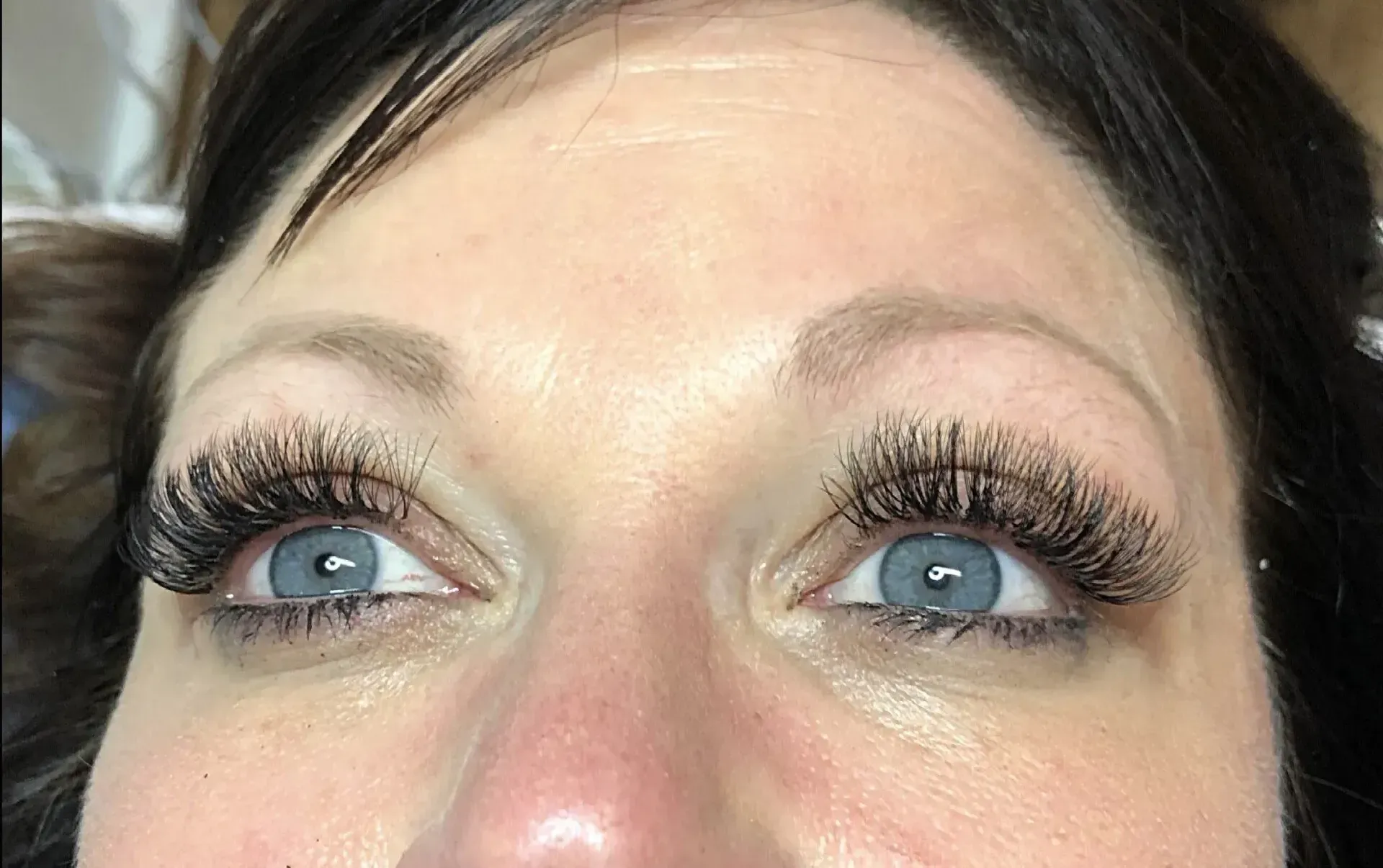 Close-up of a person’s eyes with blue irises and long eyelashes