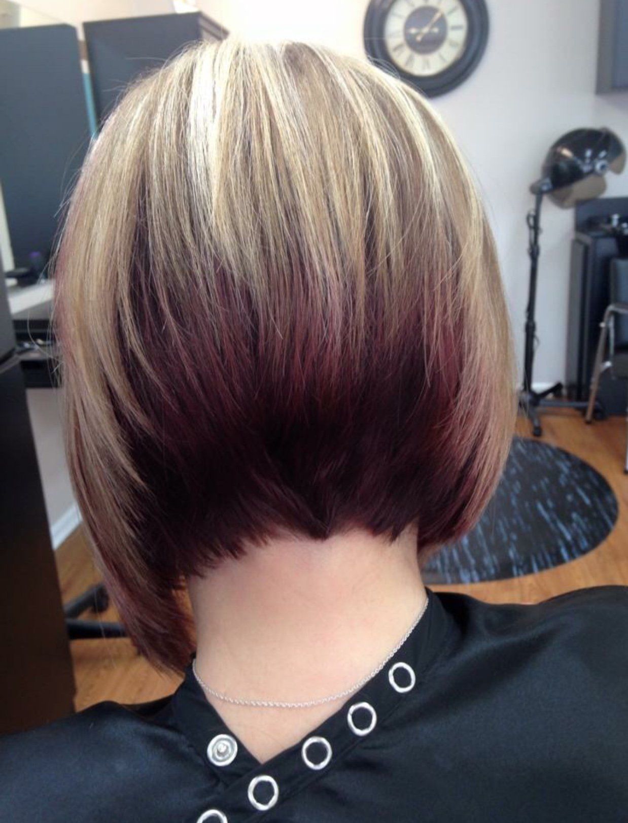 Short layered bob haircut with blonde highlights and dark burgundy lowlights, viewed from the back.