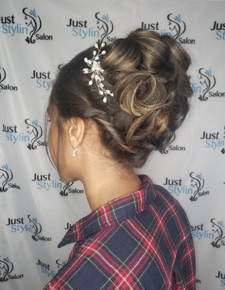 Elegant updo hairstyle with blonde highlights and curls, shown from the back against a salon backdrop