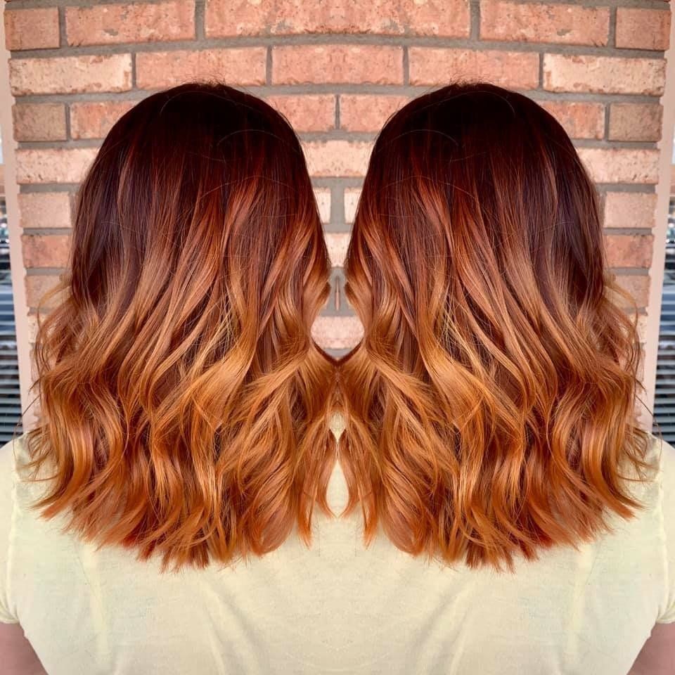 Side-by-side mirrored photo of shoulder-length wavy auburn hair with blonde highlights against a brick wall