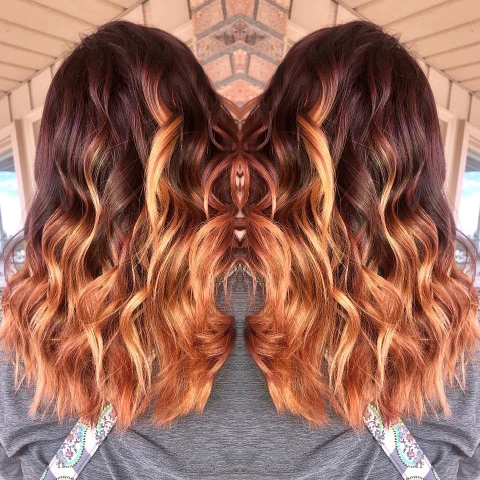 Back view of wavy shoulder-length hair dyed dark brown with copper balayage highlights
