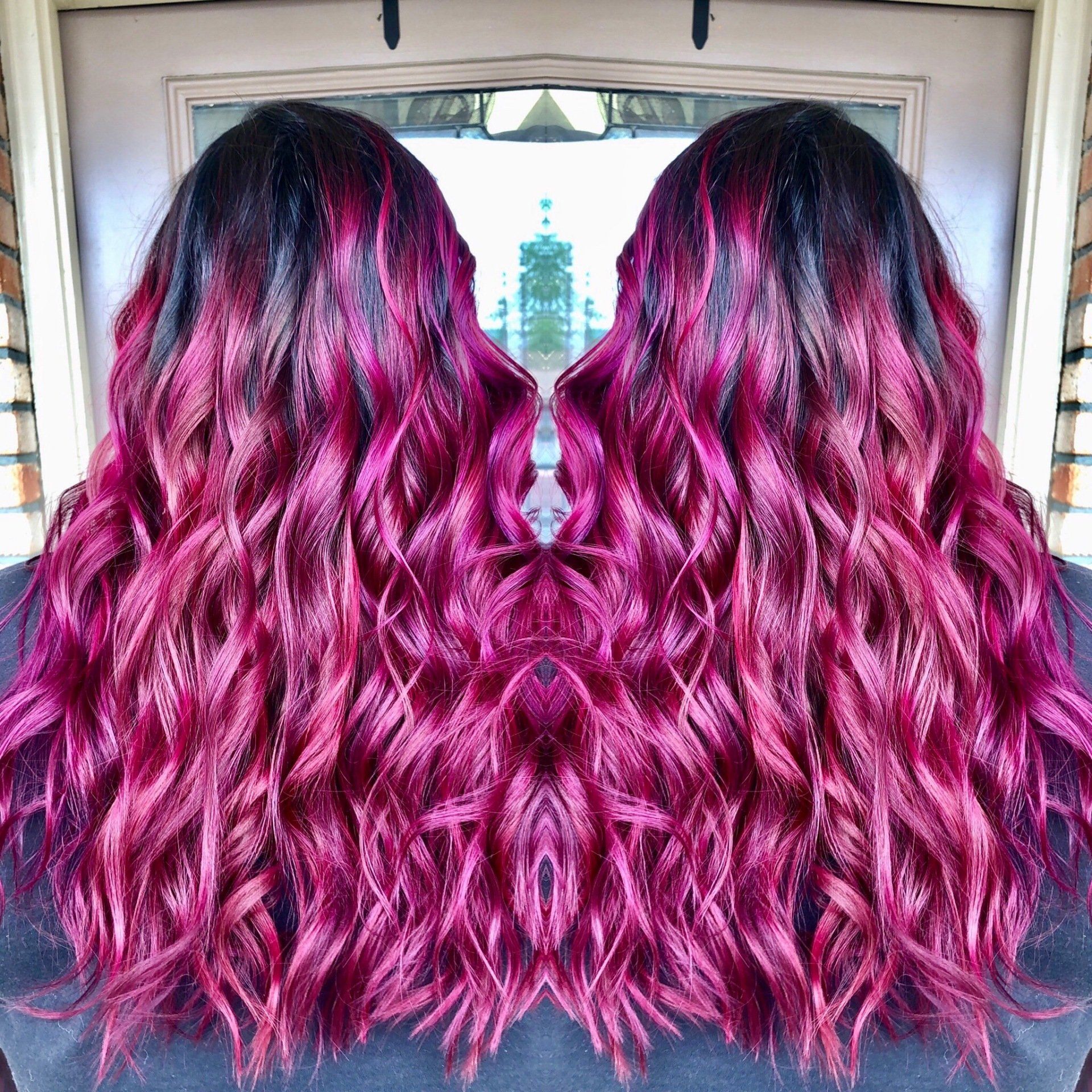 Two wavy magenta wig pieces displayed side by side against a window.