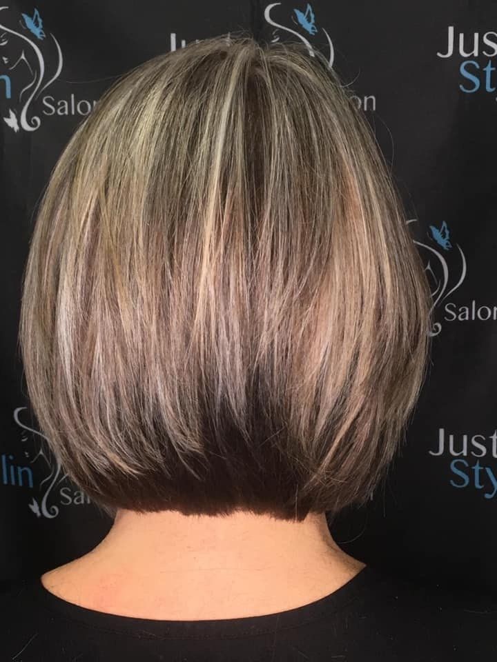 Short layered bob haircut with blonde highlights and dark lowlights, viewed from the back on a salon backdrop