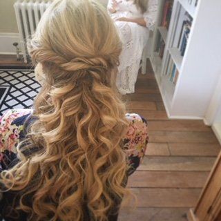 Blonde hair in a half-up braided style with loose curls, viewed from behind in a bright room.