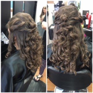 Before-and-after view of a styled brunette half-up curly hairstyle in a salon mirror