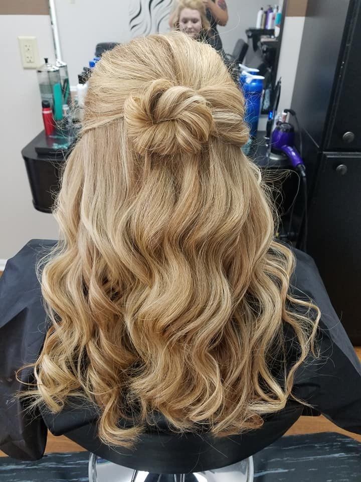 Blonde wavy half-up bun hairstyle viewed from behind in a salon chair