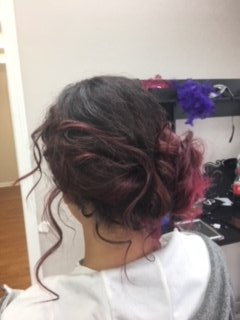 Dark curly updo with loose tendrils, viewed from behind, in a salon setting