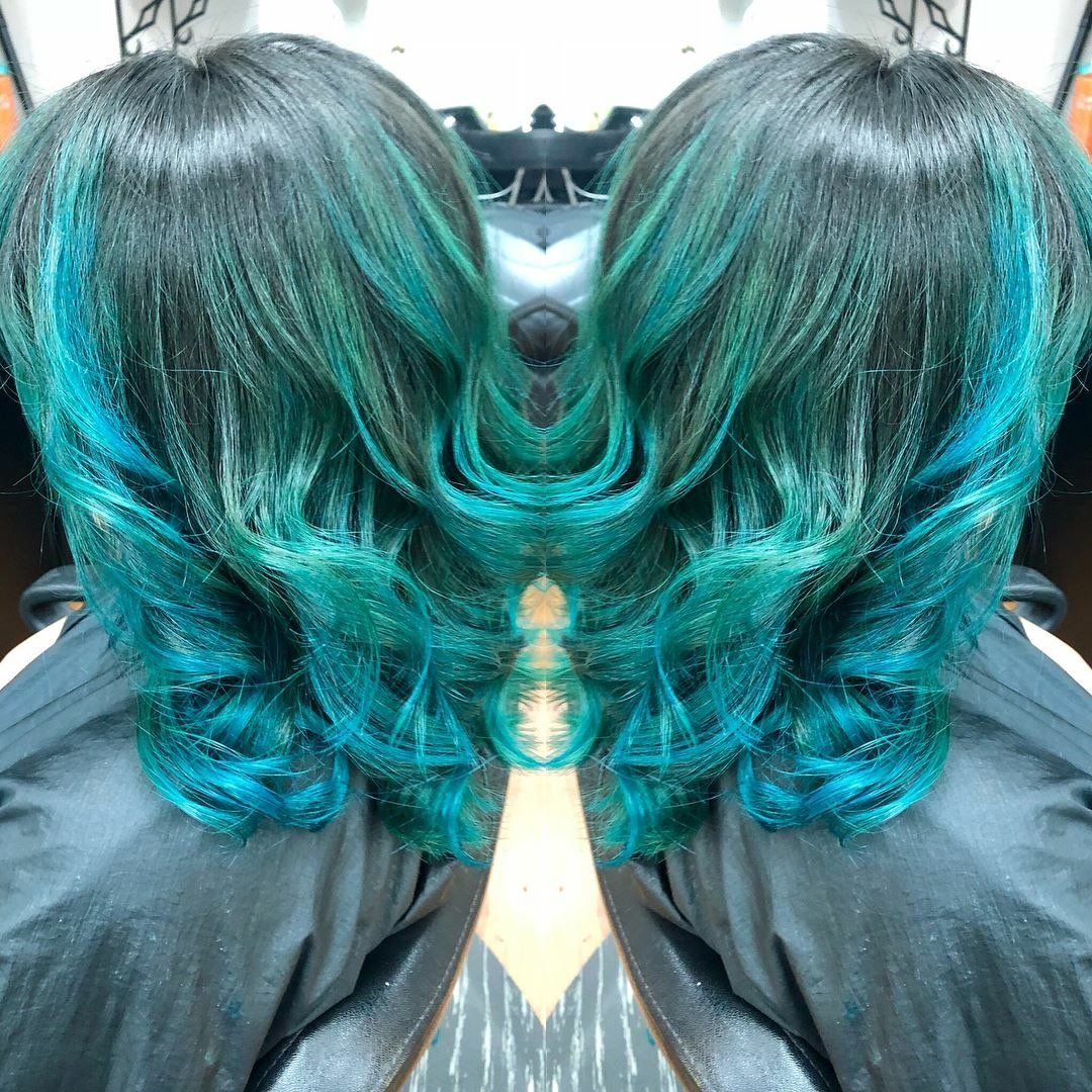 Two mirrored views of teal-tinted shoulder-length hair in a salon chair