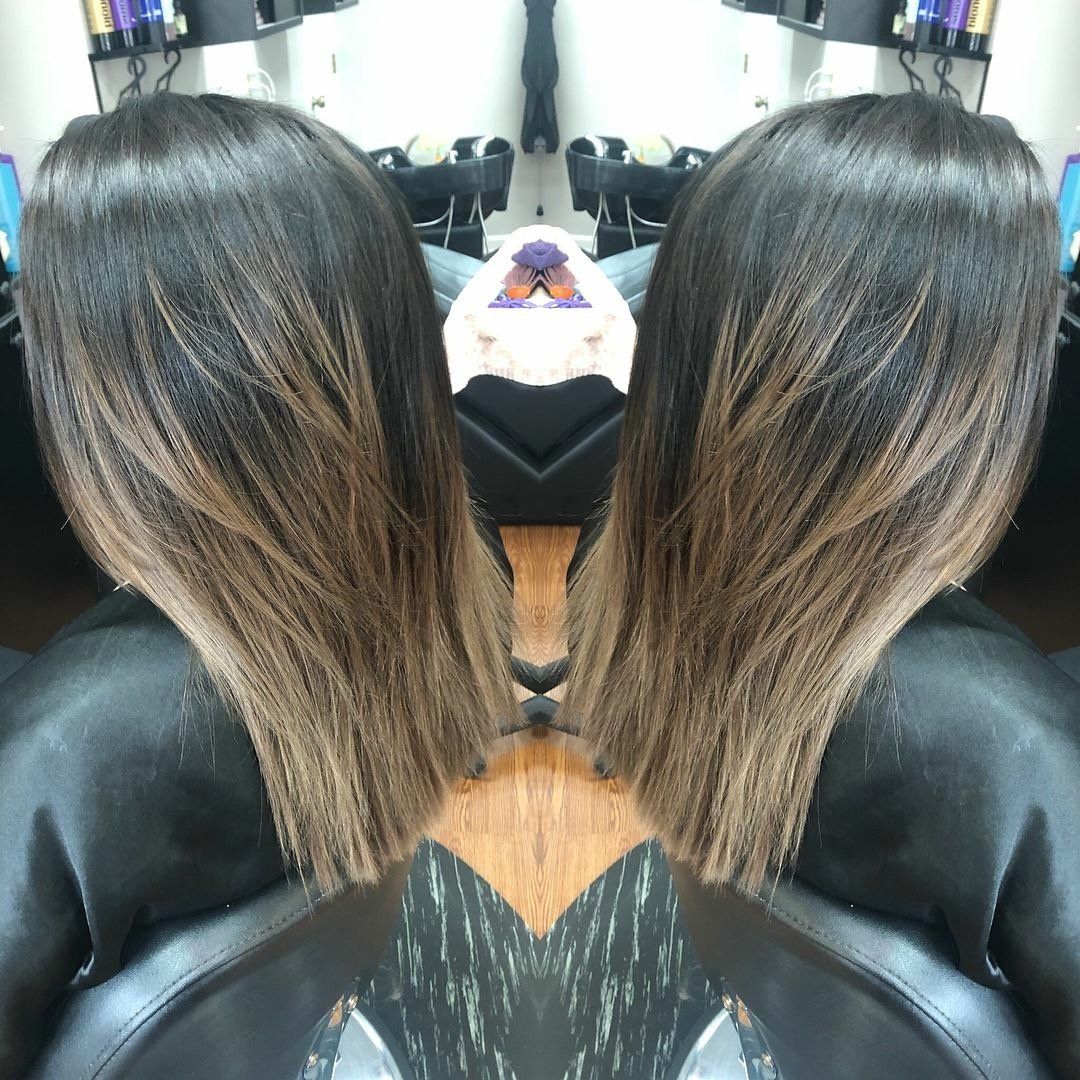 Mirrored photo of a person with long highlighted hair in a salon chair