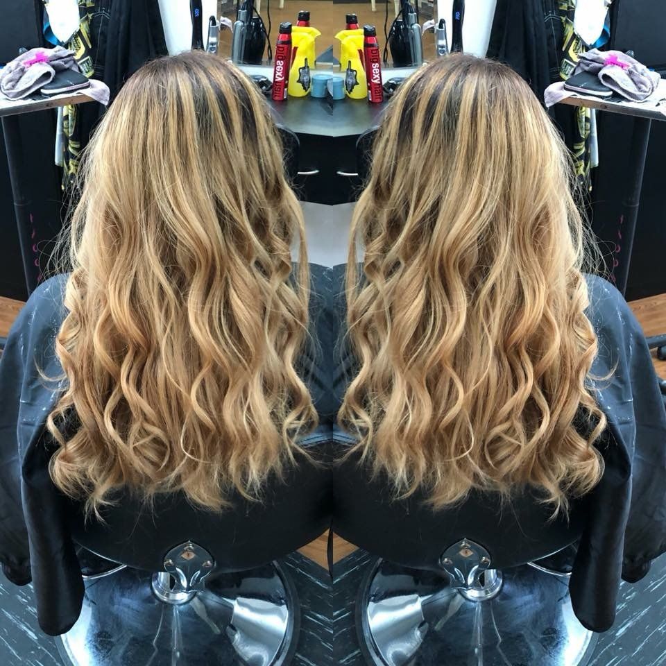 Side-by-side view of wavy blonde hair with dark roots, styled in loose waves at a salon chair.