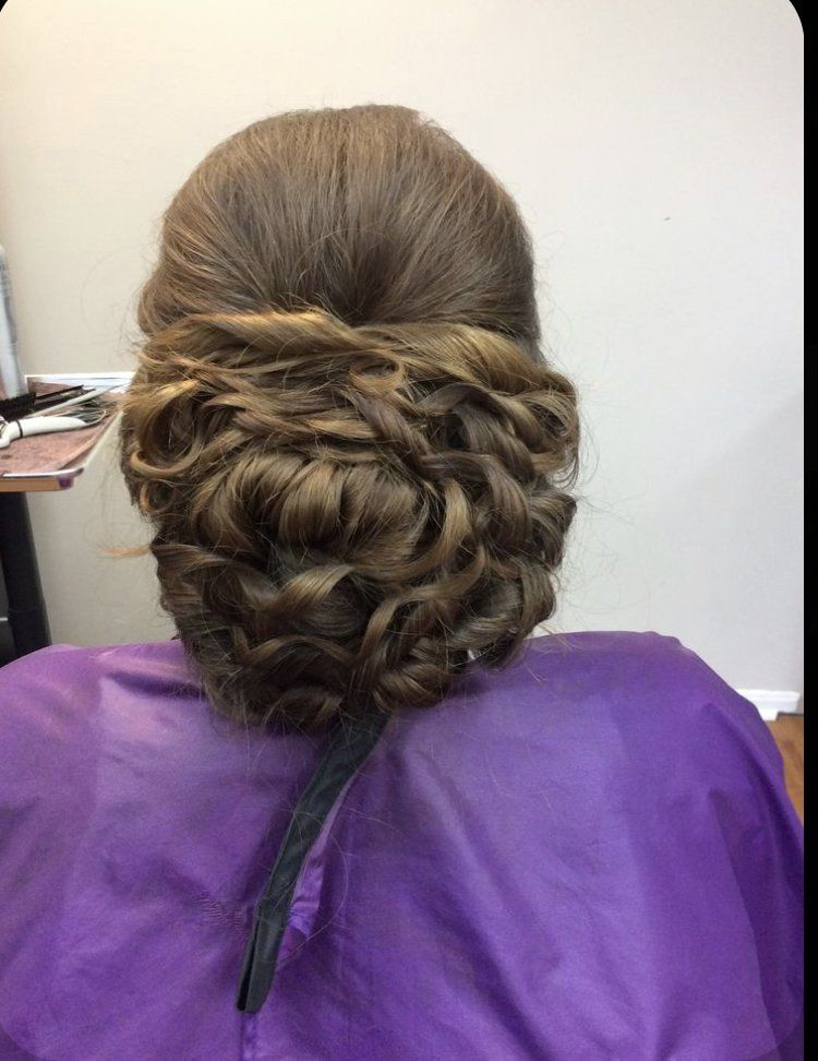 Intricate braided updo with a twisted top section, seen from the back, over a purple salon cape.