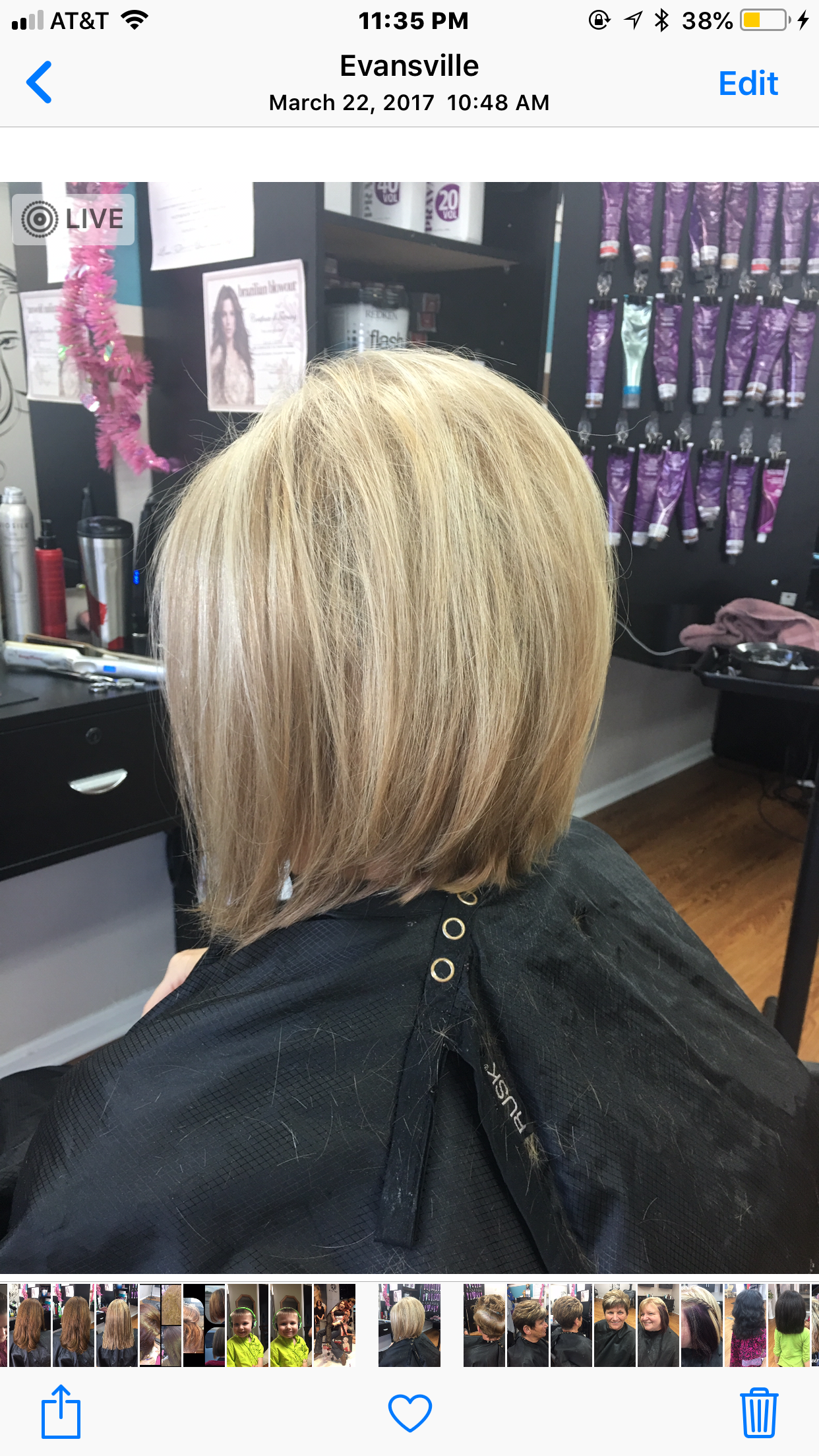 Blonde bob haircut in a salon, shown from the side with highlights and a black cape on the client.