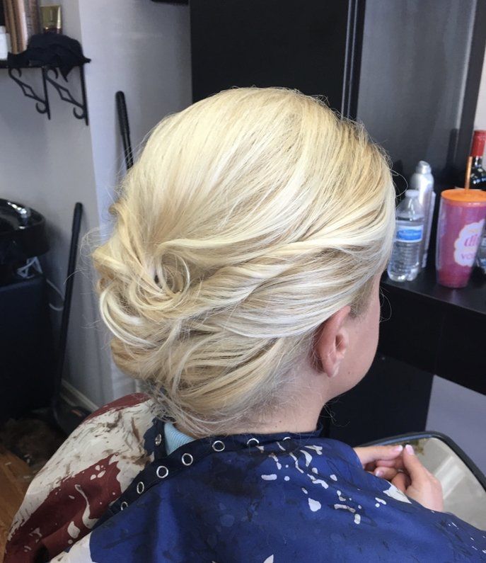 Blonde hair styled in a low twisted updo, viewed from behind in a salon chair.