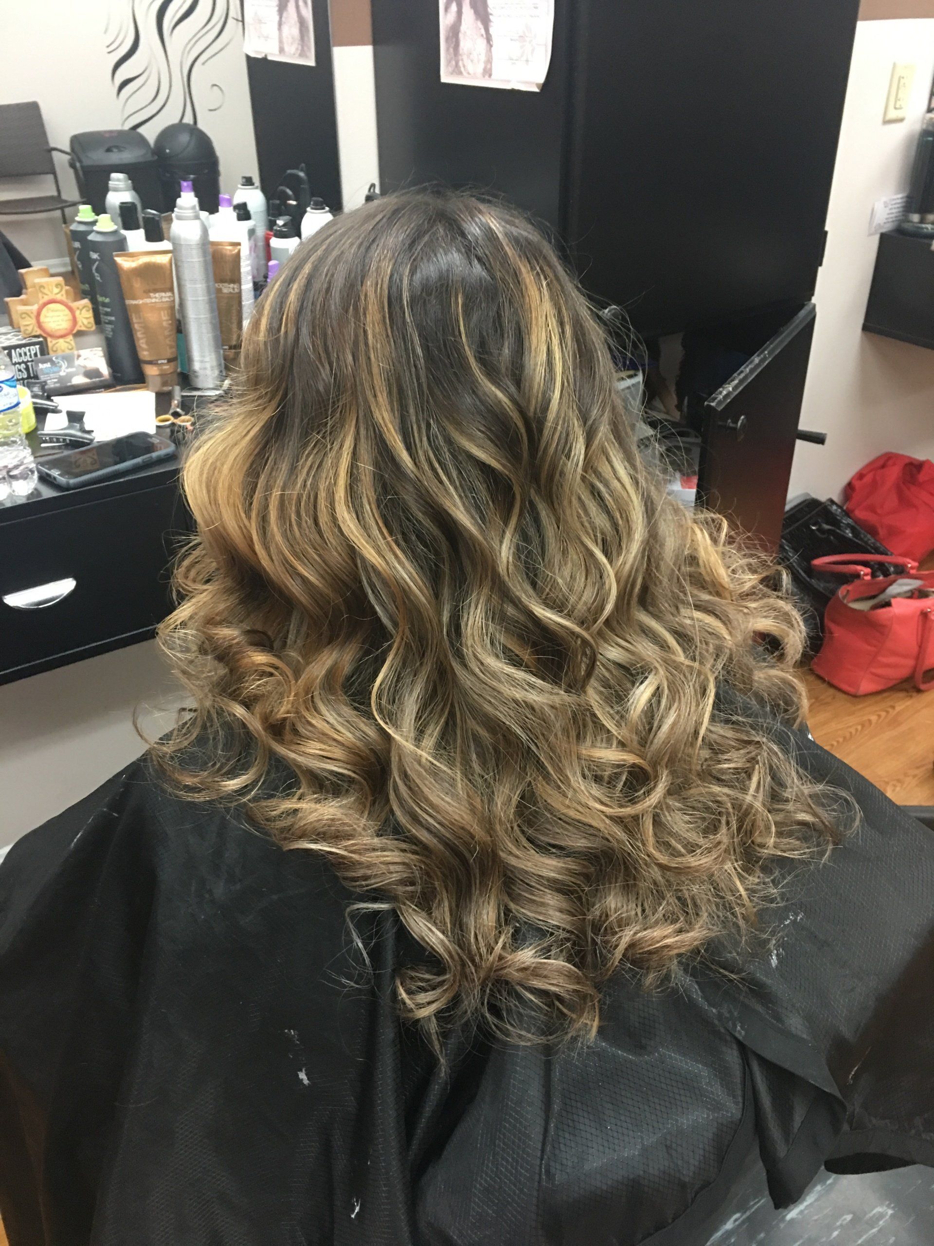 Curly highlighted hair styled in loose waves at a salon station
