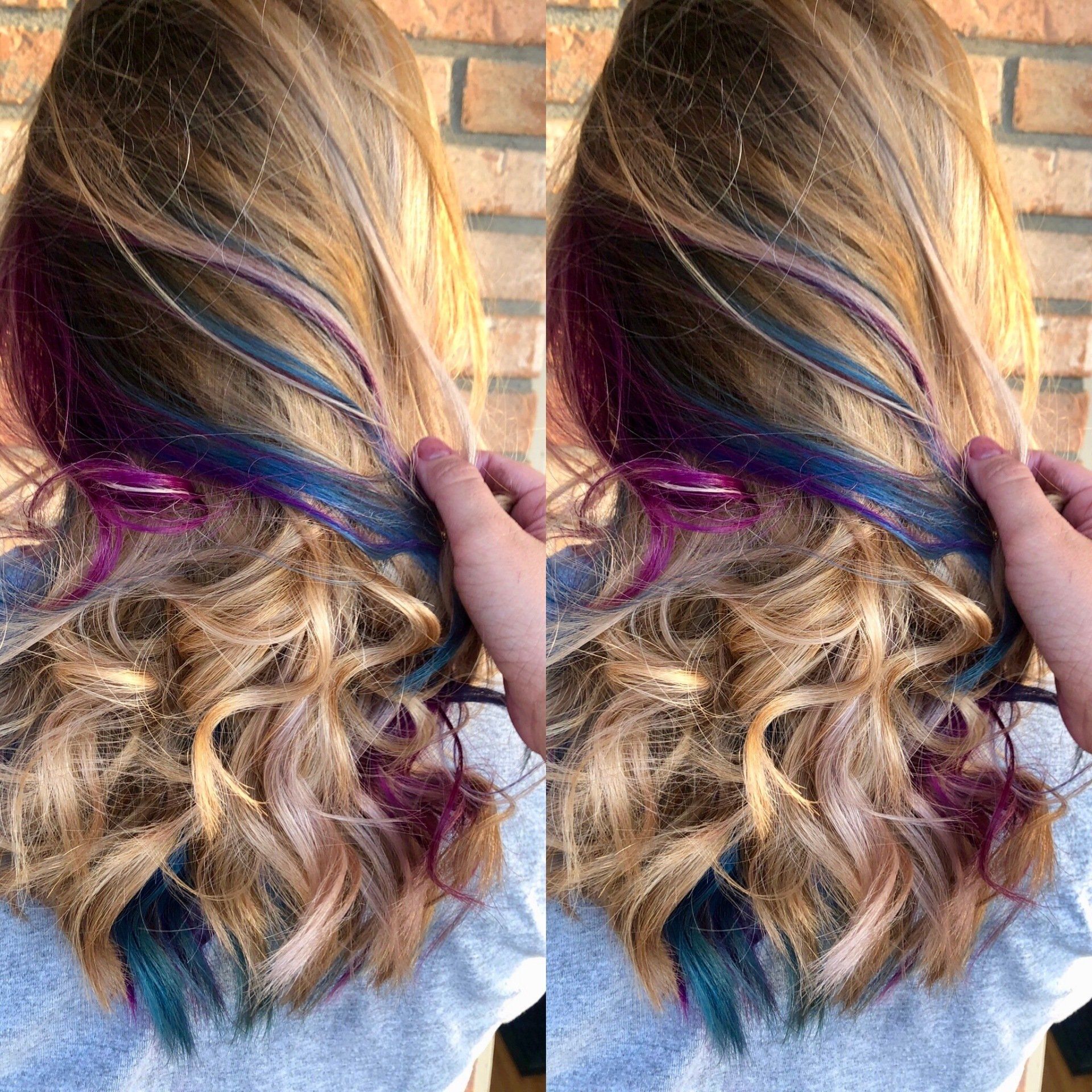 Wavy hair with vibrant purple, blue, and teal highlights against a brick wall